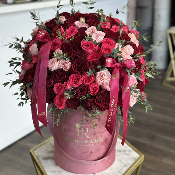 Large bouquet of red and pink roses in a pink hatbox with ribbons