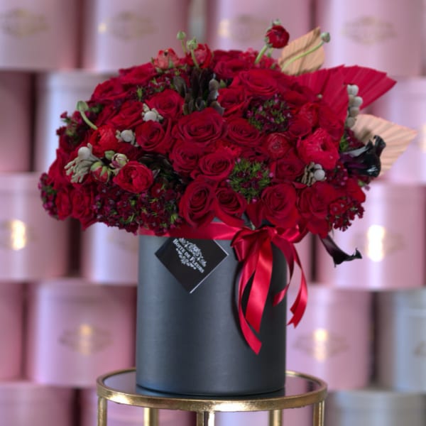 Large red rose bouquet in a black hat box with ribbon