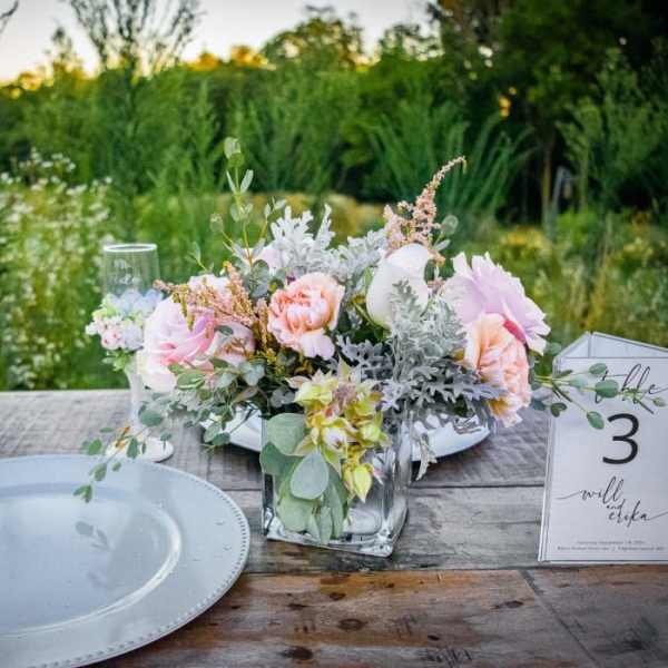 Pastel floral centerpiece in a clear glass vase on a table with a place card
