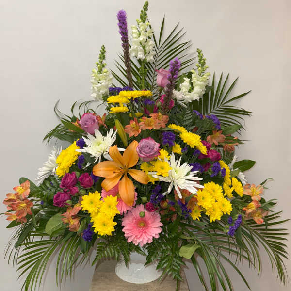 Large mixed flower arrangement in a white vase with lilies and daisies