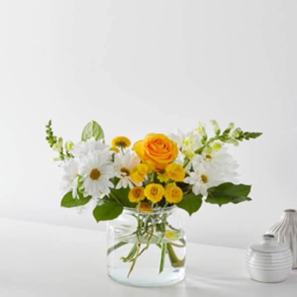 Yellow and white flowers arranged in a clear glass vase