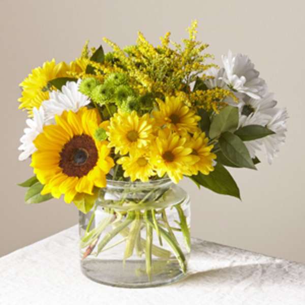 Yellow and white flowers arranged in a clear glass vase