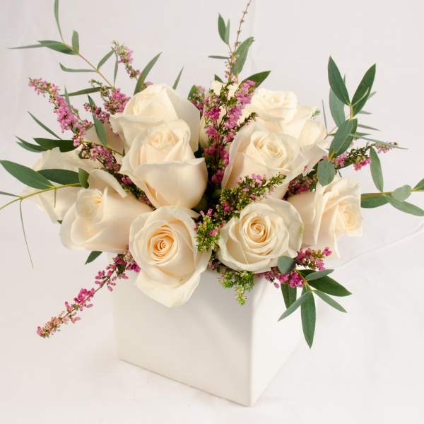 Cream roses with pink filler flowers in a white box vase