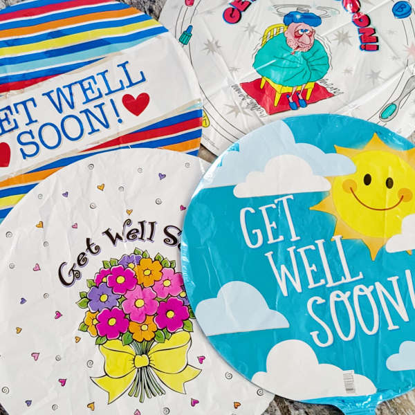 Four round get-well balloons with colorful printed designs