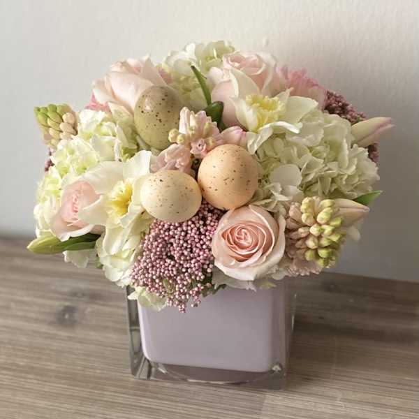 Pastel flower arrangement in a square glass vase with decorative eggs