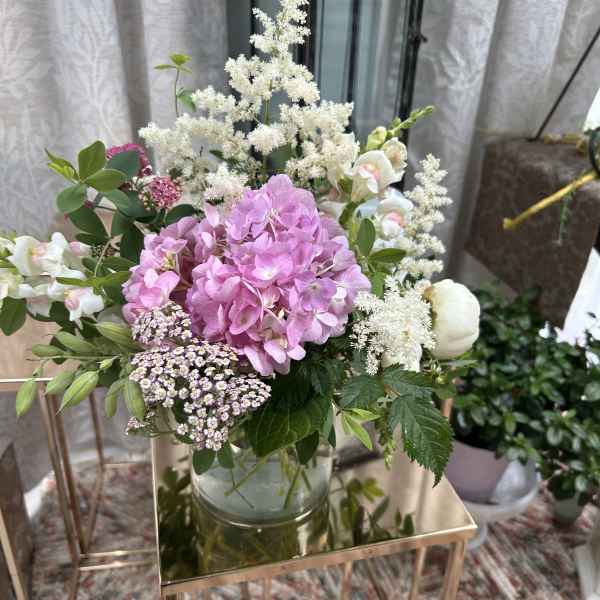 Pink hydrangea bouquet in a glass vase with white filler flowers