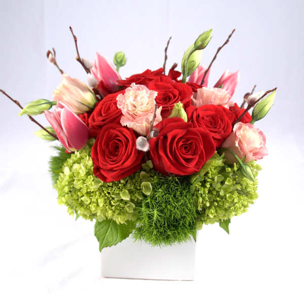 Red roses and pink tulips in a white square vase