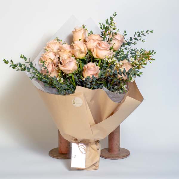 Bouquet of pale peach roses wrapped in tan paper