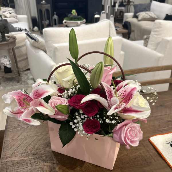 Pink and white lilies and roses in a pink handled box