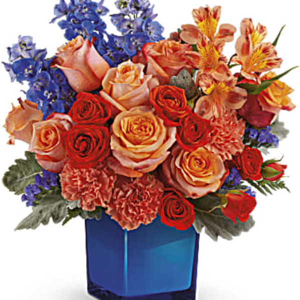 Mixed bouquet of roses, carnations, and blue flowers in a blue vase