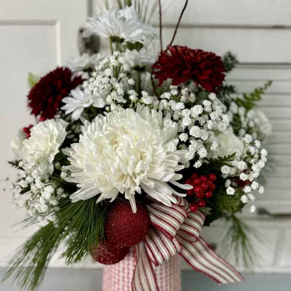 Red and white floral arrangement in a striped ribbon-wrapped container