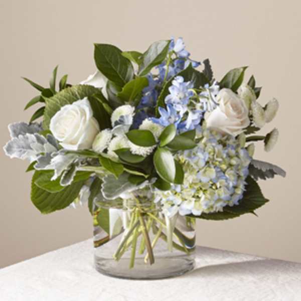 White roses and blue hydrangeas in a clear glass vase