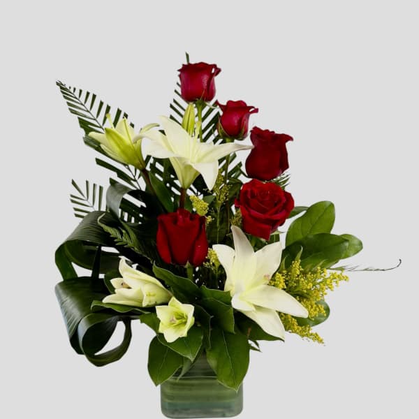 Red roses and white lilies arranged in a glass vase