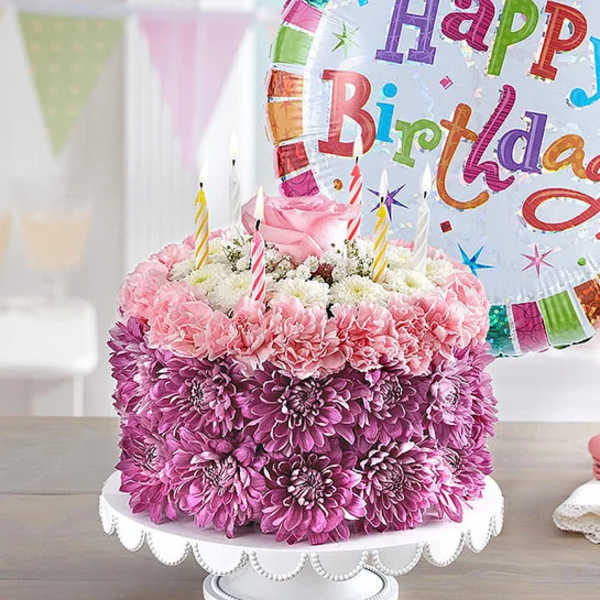 Pink and purple flower cake with birthday candles and a balloon