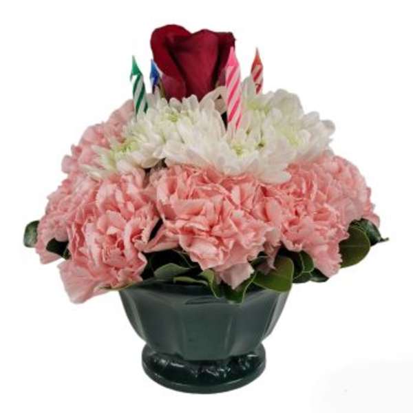 Pink and white floral arrangement in a dark vase with birthday candles