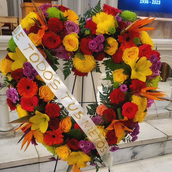 Large heart-shaped floral wreath on an easel with a memorial ribbon