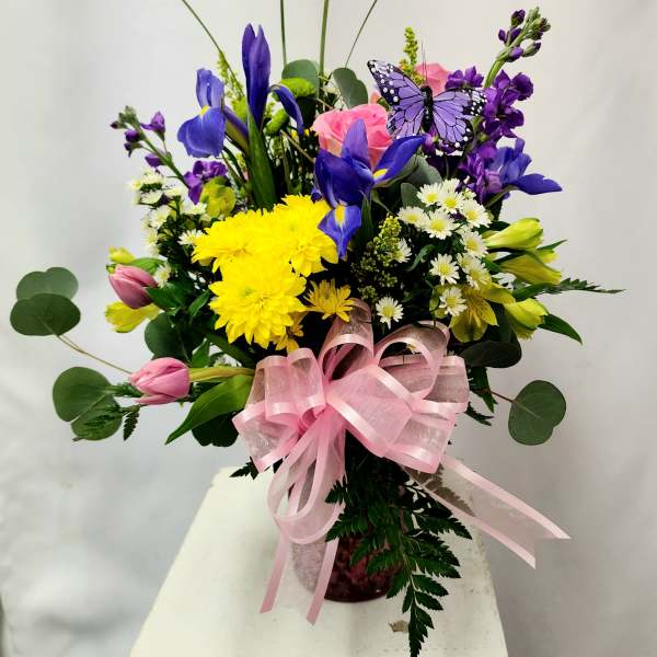 Colorful bouquet with purple irises, yellow chrysanthemums, pink tulips, and a pink ribbon