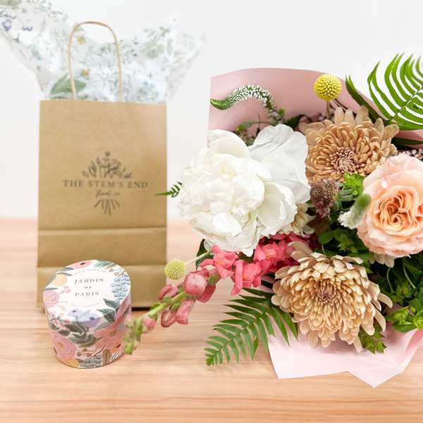 Bouquet of peach and white flowers with a candle and gift bag