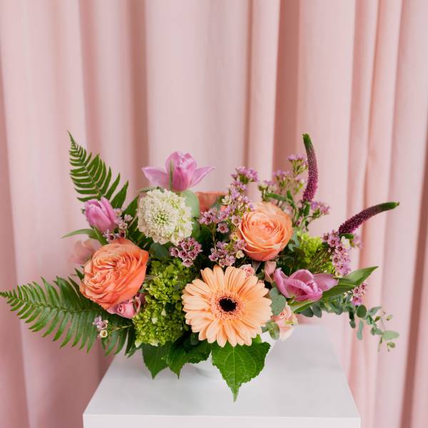 Pink and peach floral arrangement in a white vase