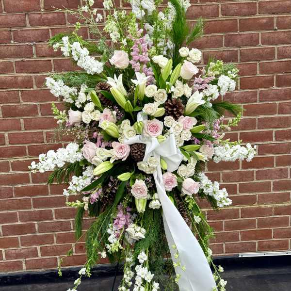 Large standing floral spray with pink and white flowers on a black easel