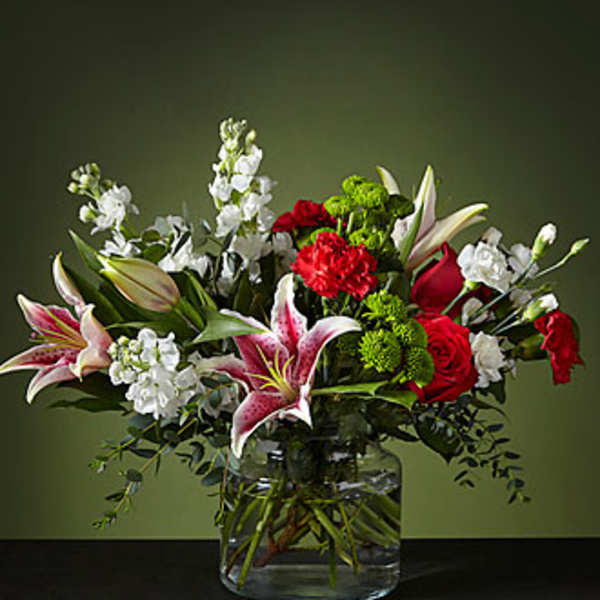 Bouquet of red roses, pink lilies, and white flowers in a glass vase