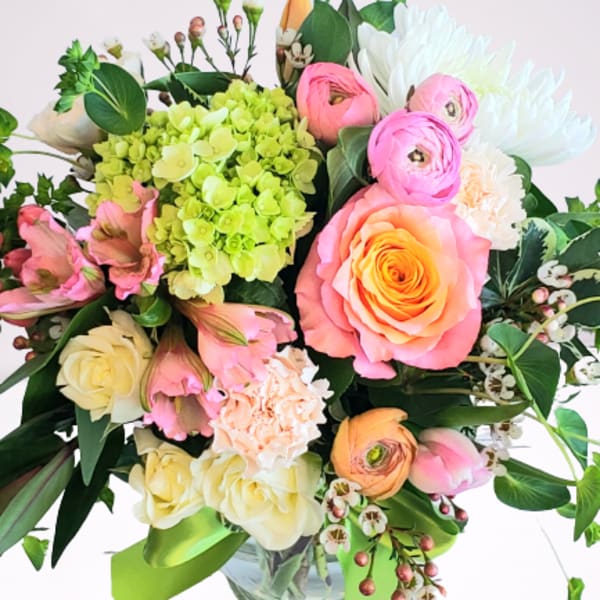 Mixed bouquet of pink, white, and green flowers in a glass vase