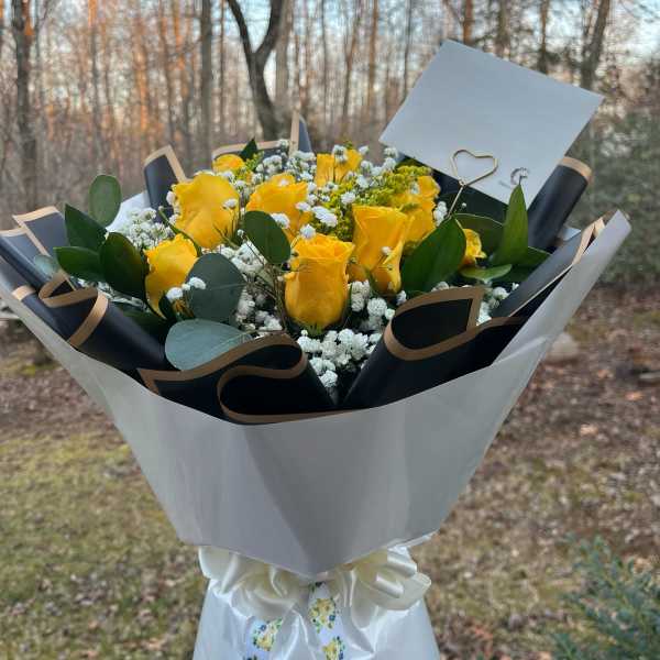Bouquet of yellow roses with white baby's breath in black and white wrap