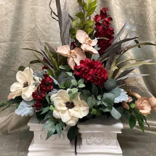 Floral arrangement with cream and burgundy blooms in white pedestal containers