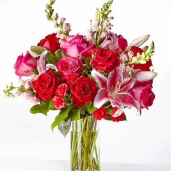 Bouquet of red and pink roses with lilies in a clear glass vase
