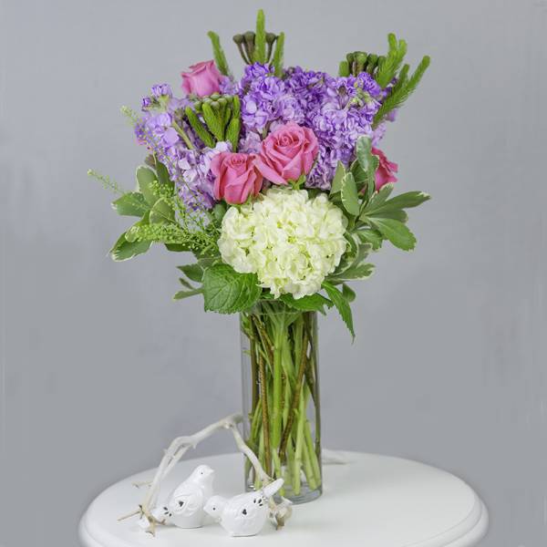 Bouquet of pink roses and purple hydrangeas in a clear glass vase