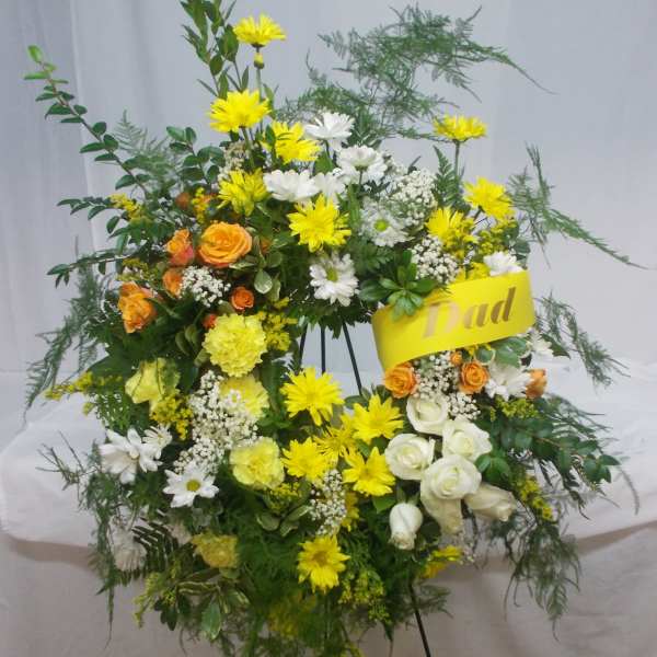 Standing floral spray with yellow, white, and orange flowers on an easel