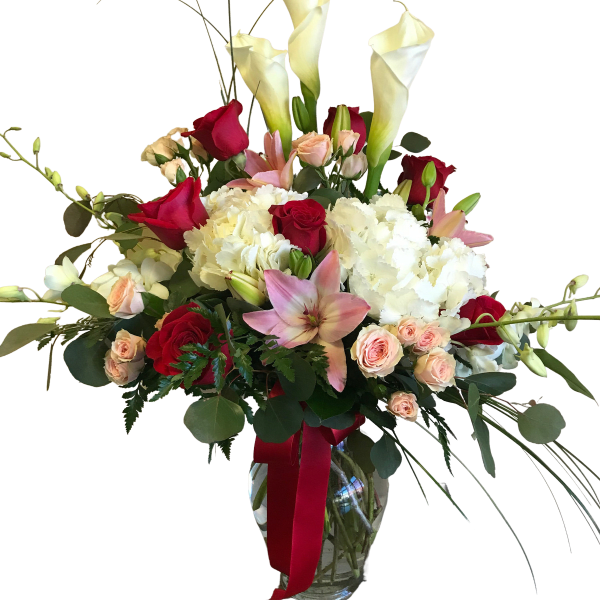 Tall bouquet of white calla lilies, red roses, and pink lilies in a glass vase