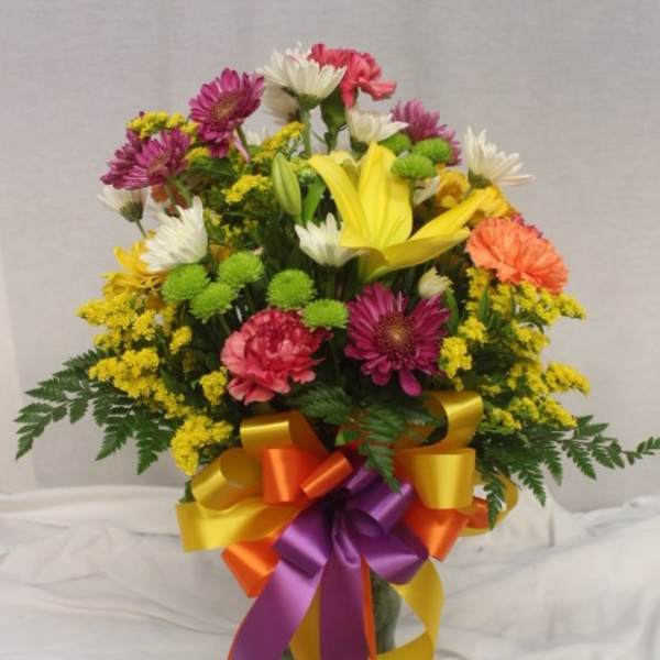Mixed bouquet in a glass vase with a multicolored ribbon bow
