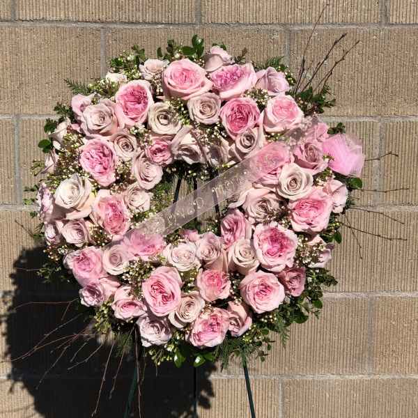 Heart-shaped pink rose wreath with a ribbon on a stand