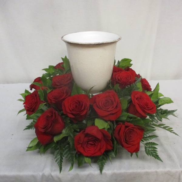Red roses arranged around a white urn vase