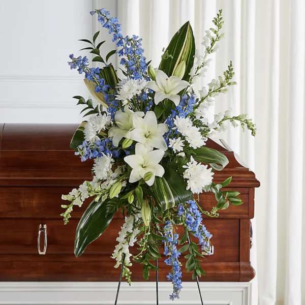 White lilies and blue flowers arranged on a casket