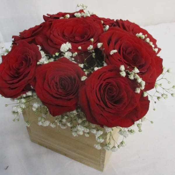 Red roses arranged in a wooden box with white baby's breath