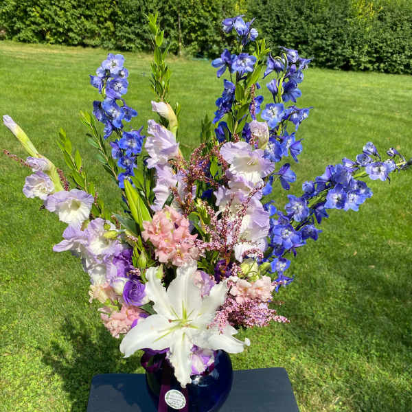 Tall bouquet of blue and lavender flowers in a dark vase