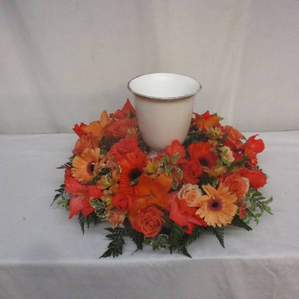 Orange floral wreath around a white urn-shaped vase