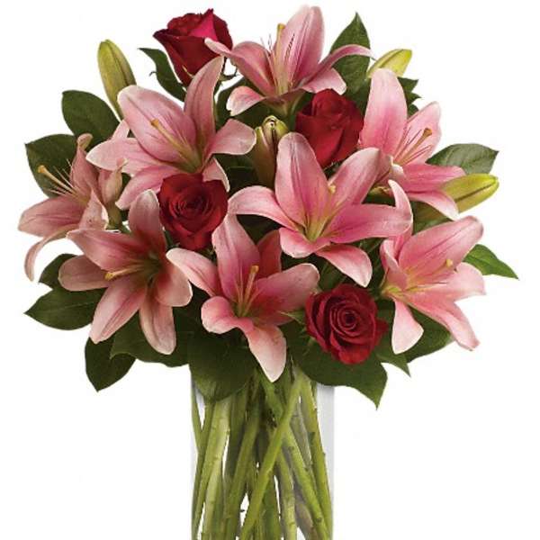 Pink lilies and red roses in a clear glass vase