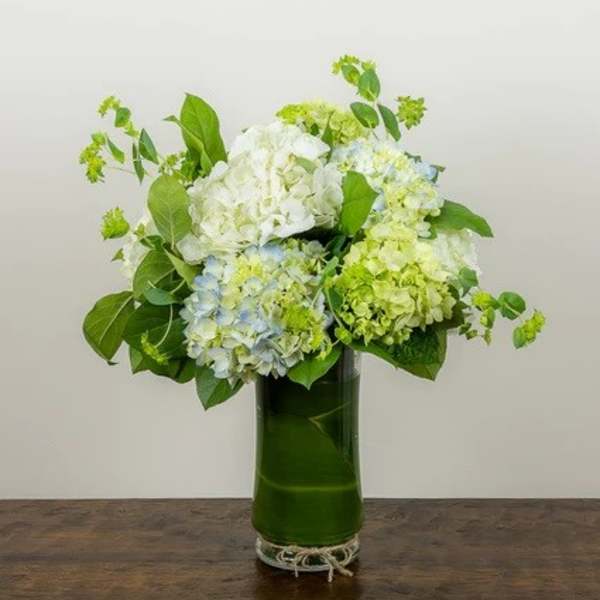 Hydrangea arrangement in a tall green glass vase