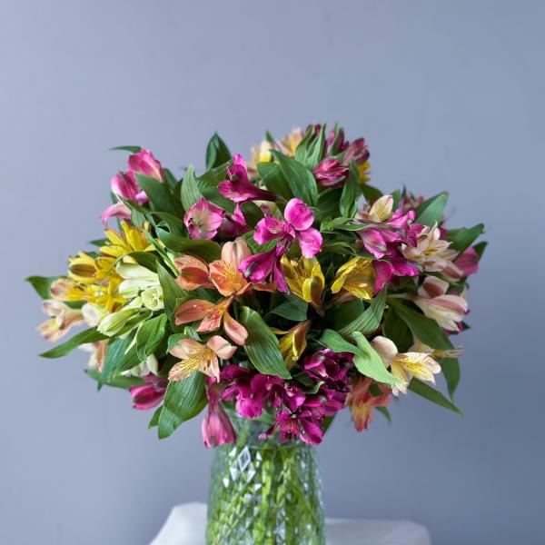Bouquet of pink, yellow, and peach flowers in a glass vase