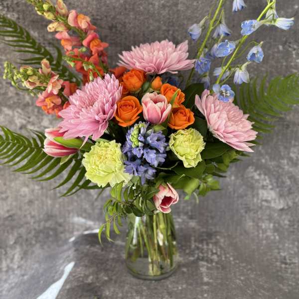 Mixed bouquet in a glass vase with pink, orange, and blue flowers