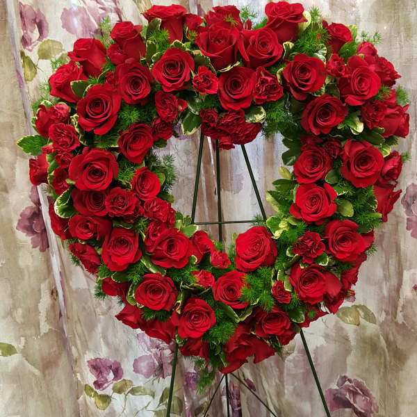 Heart-shaped wreath of red roses on a metal stand