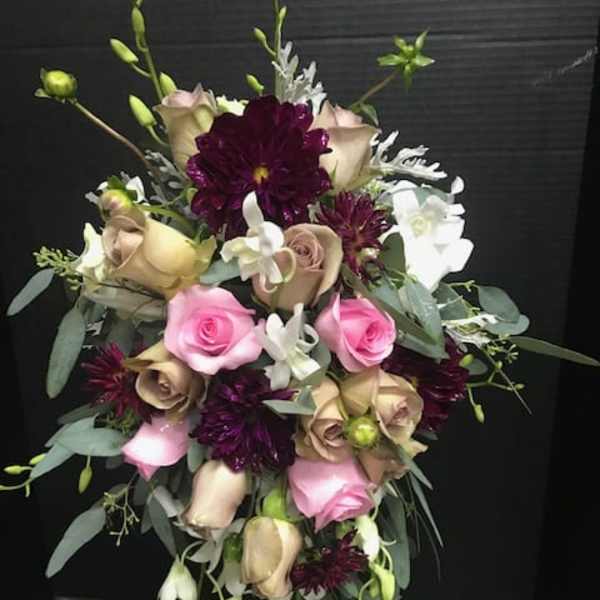 Bouquet of pink and beige roses with dark purple blooms