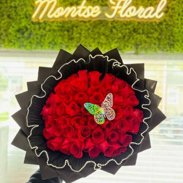 Red rose bouquet wrapped in black paper with a butterfly accent