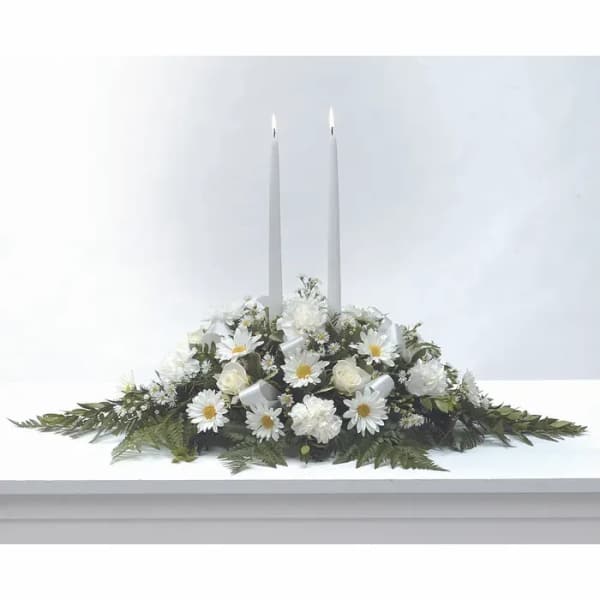 White floral centerpiece with two tall taper candles