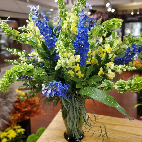 Tall bouquet of blue and yellow flowers in a glass vase