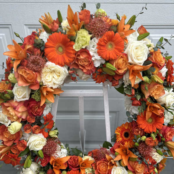 Orange and white floral wreath with roses and lilies