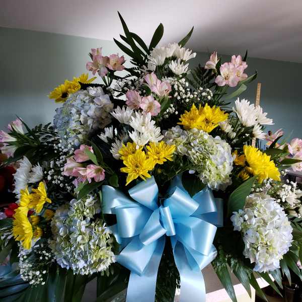 Large mixed flower arrangement with a blue ribbon bow